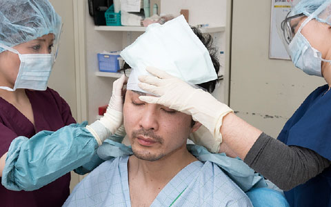 ナースが患者様の術部に包帯を取り付けている様子の写真