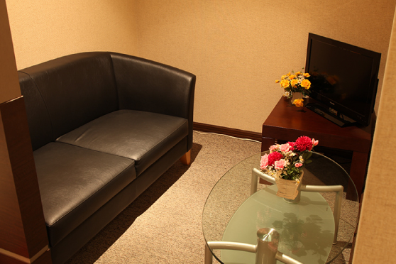 名古屋院 待合室の写真。黒い大きなソファにガラス製のモダンなテーブルがあります。